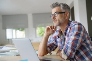 a middle aged man with a laptop, thinking