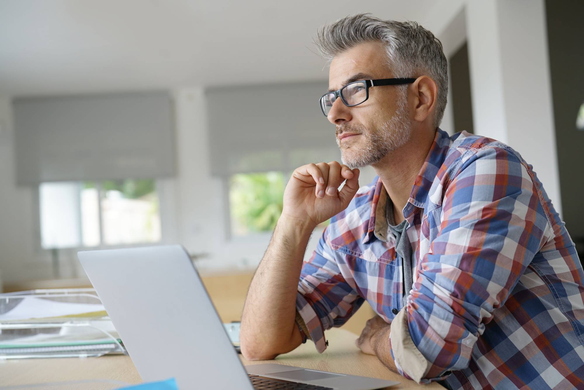 a middle aged man with a laptop, thinking