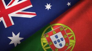 Flags of Australia and Portugal are shown side by side, with the top half of the image featuring the Australian flag with its Union Jack and stars, and the bottom half displaying the Portuguese flag with its red and green sections and the national coat of arms.