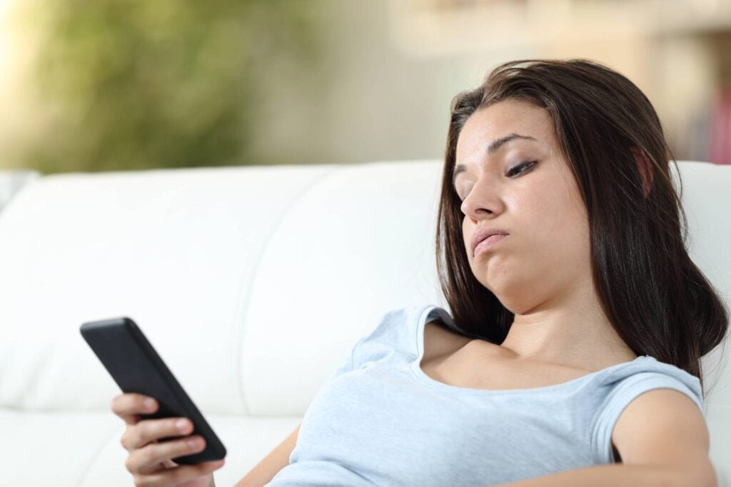 bored girl staring at her phone.