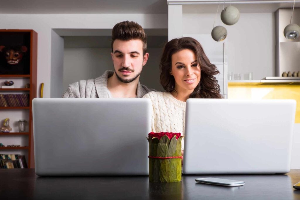 a couple both looking at their laptops and trying to make a decision