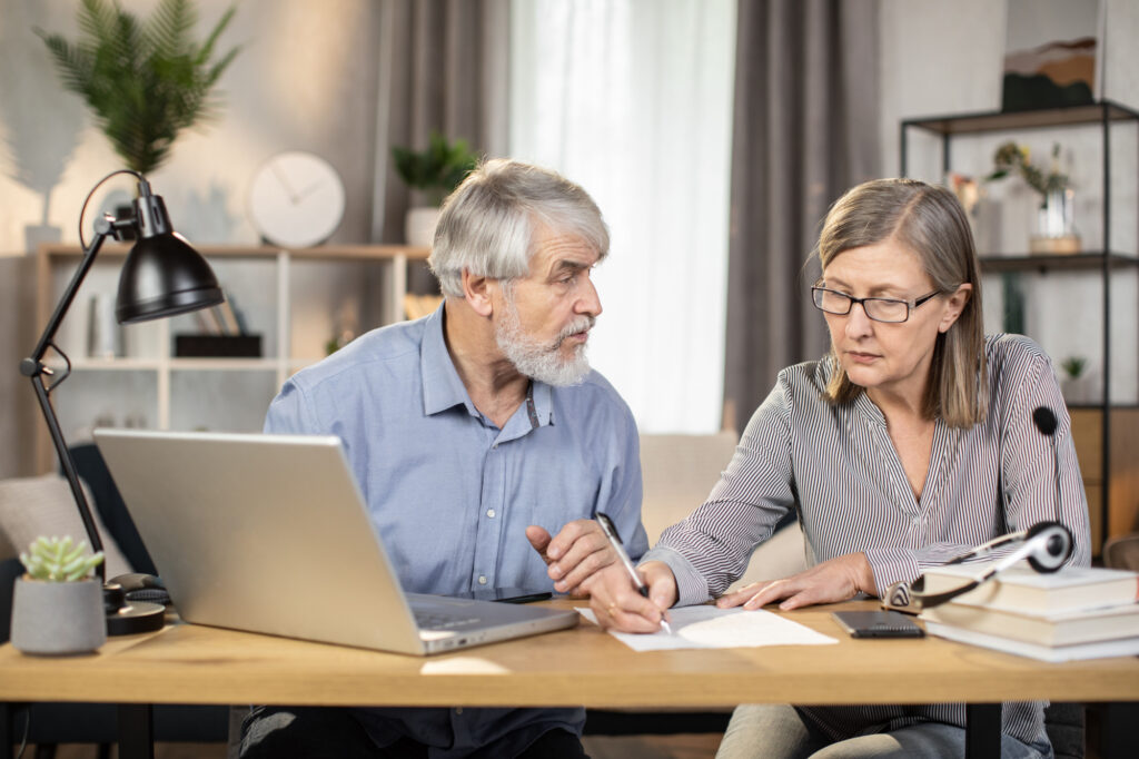 older couple budgeting at a table in front of a laptop