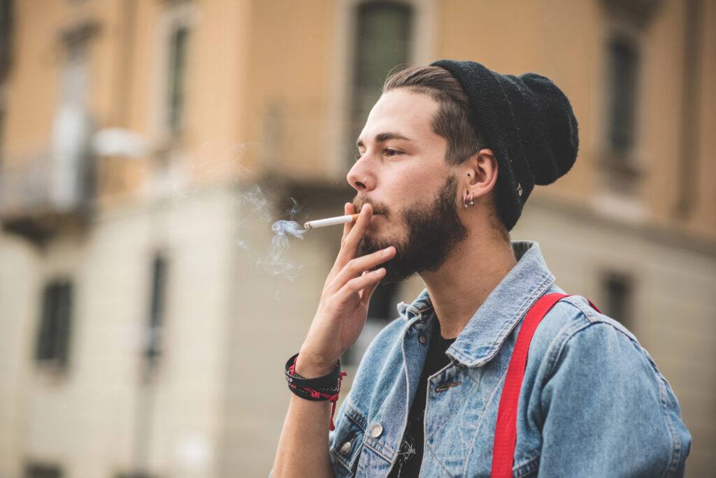 A European-looking man smoking outside in a street