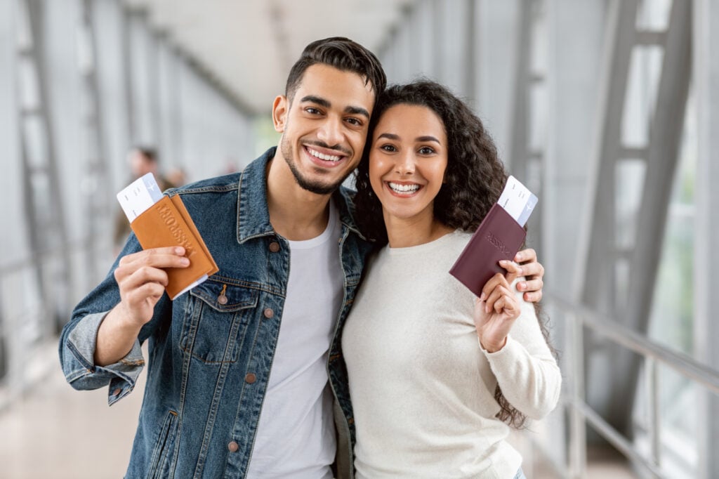 A Couple holding passports at an airport with boarding passes inside.