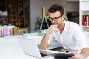 Man looking at his laptop and a file