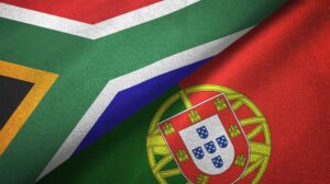 Two flags are shown overlapping: on the left, the flag of South Africa with a green, white, red, yellow, blue, and black design, and on the right, the flag of Portugal with a red background and a coat of arms featuring a shield and armillary sphere.